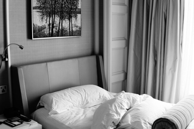 selected-01-quiet-hotel-bedroom-interior-optimized Lugnt hotellrum med bäddad säng, tjocka gardiner och stoppad sänggavel