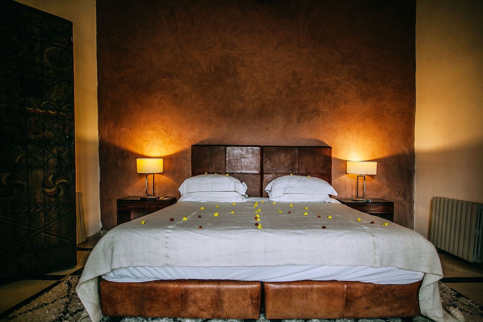 Romantiskt hotellrum med bäddad säng, blommor och varm belysning