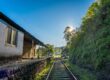 Historisk järnvägsstation med räls och grönskande berg i bakgrunden